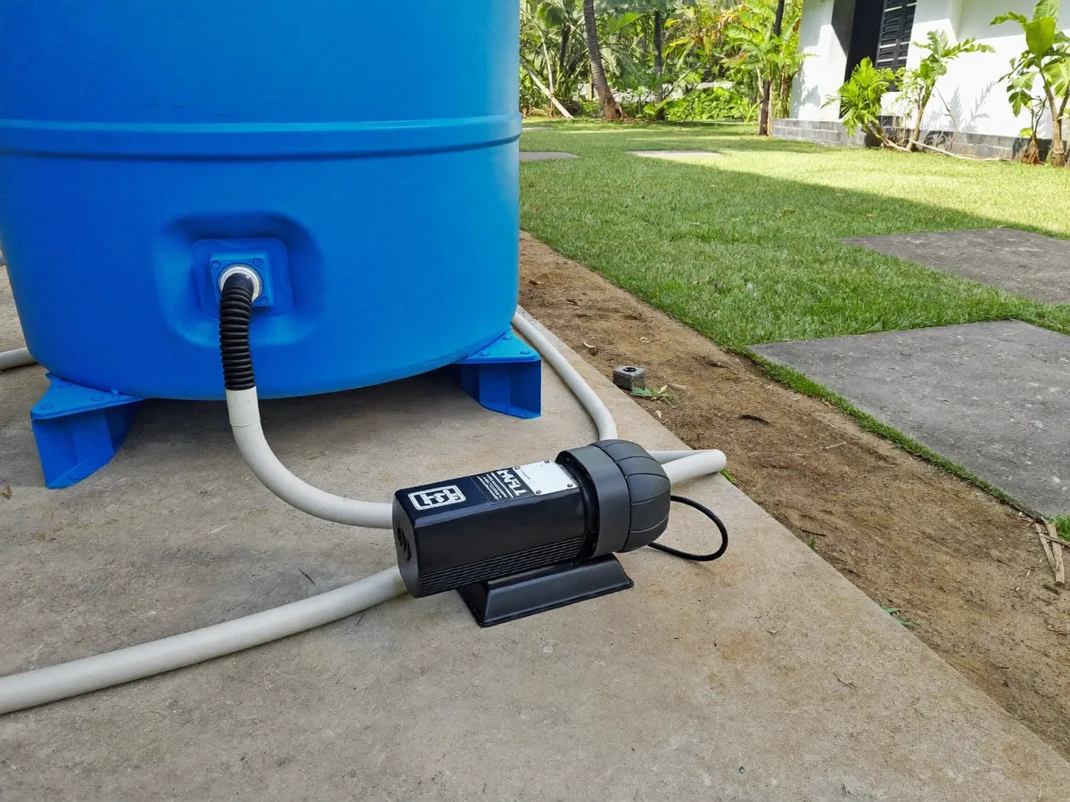Water pressure booster pump and blue storage tank outside a Bali villa