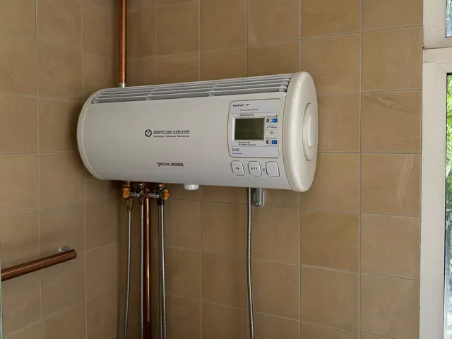 White electric water heater on a tiled bathroom wall